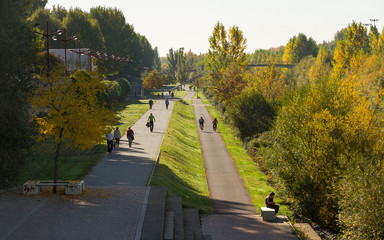 Actividad de mañana en un paseo peatonal y carril bici al lado del río en otoño.  Gente...