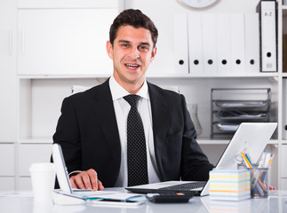 Smiling manager working on laptop