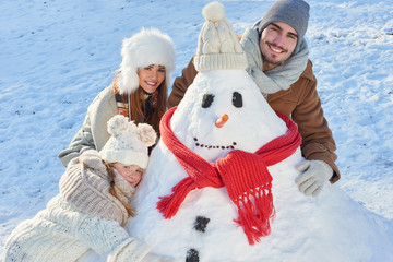 Glückliche Familie beim Schneemann bauen