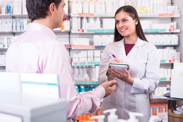 Pharmacist and customer in drugstore .