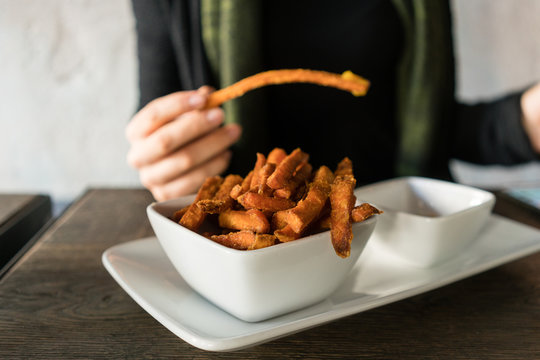 Frau isst S&uuml;&szlig;kartoffel Fritten im Restaurant mit Dip