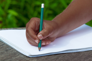 black kid's hand draws in pencil