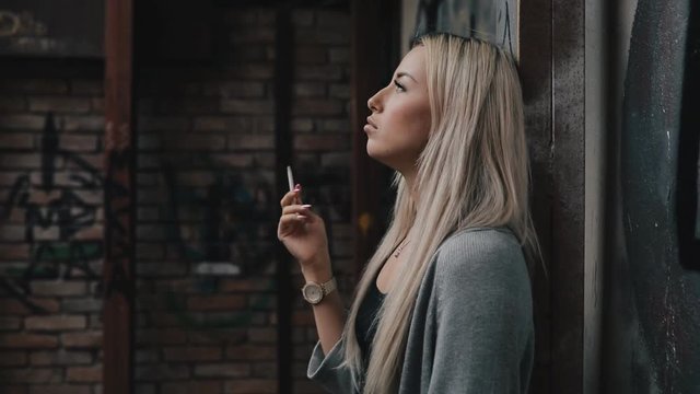Bad addiction. Woman smoke a cigarette in a side street.