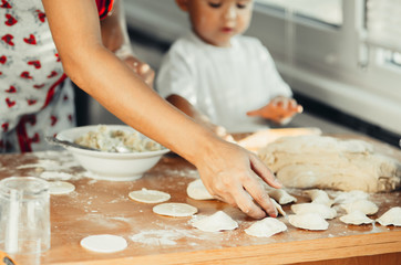 Obraz na płótnie Canvas Little boy with mom in the kitchen preparing dough