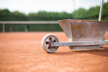 A worker repairing / powdering the lines of clay tennis court by white powder