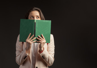young woman with book looking right on dark background