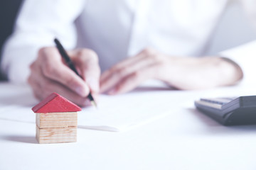 businessman signs contract behind home architectural model