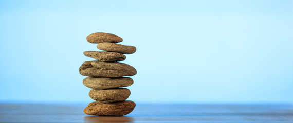 Zen stones stack on blue sky and sea background