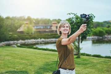 Woman capturing herself with small personal camera in a park