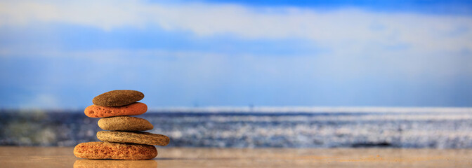 Zen stones stack on blue sky and sea background