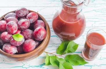 Plums in a wooden Cup and prune juice on white background
