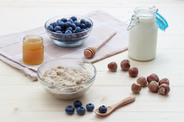 Breakfast of oatmeal with blueberries, honey, milk and hazelnuts