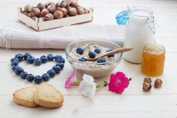 Breakfast of love from oatmeal blueberries with hearts, honey, nuts and milk.
