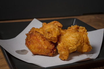 Fried chicken wings on a black plate, on a wooden table.