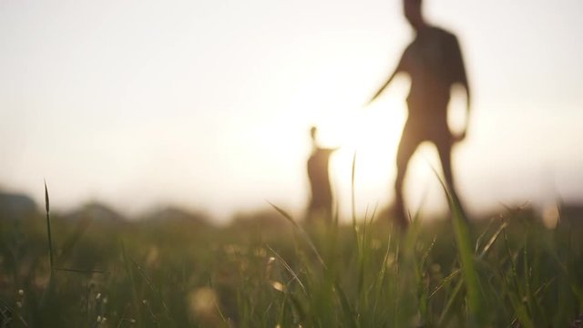 Blurry view of man and little boy having fun running down the field on horizon slow motion. Concept of friendly family.