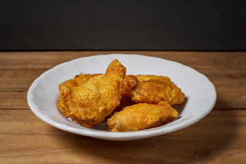 Fried chicken wings on a white plate, on a wooden table.
