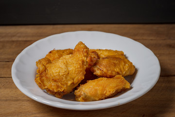 Fried chicken wings on a white plate, on a wooden table.