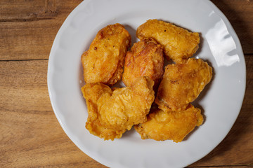 Fried chicken wings on a white plate, on a wooden table.
