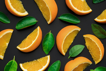 Colorful fruit of fresh orange slices with leaf on black background.