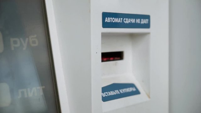 The guy inserts money into the bill acceptor close-up. The young man pays for gasoline. Self-service station.