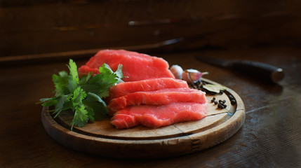 Meat, sliced on a board with herbs and spices