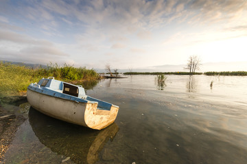 Image of an abandoned boat on the lake in morning sunlight
