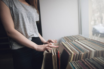 Choosing retro vinyl records. Music background. Unrecognizable woman in musical shop, old school hipster style