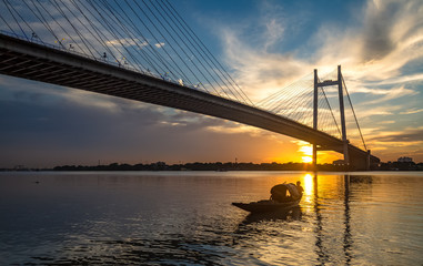 Fototapeta na wymiar Wooden boat near Vidyasagar setu bridge on river Hooghly at sunset.
