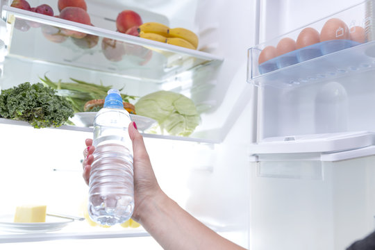 Woman taking a water bottle out of the fridge
