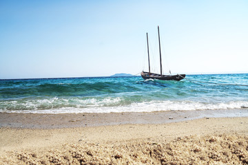 Image of rustic wooden sailing boat floating on the waves of unrest sea