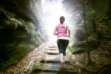 Frau die Bergauf in die Sonne läuft 