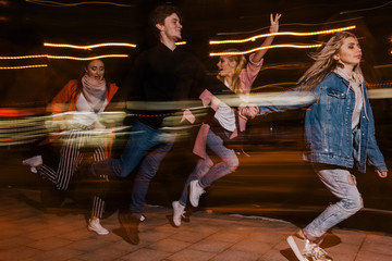 Youth movement in night city. Blurred background. Friends party, happy students outdoors, strong...