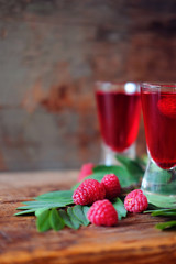 Raspberry fruit liqueur in two shot glasses with berries and green leaves