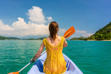 Rear view of a young woman paddling a canoe on the sea in a sunny day during vacation in Flores Island, Indonesia
