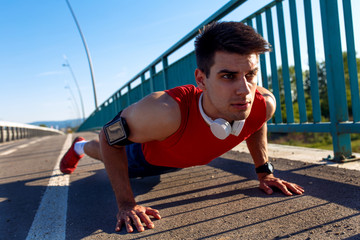 Portrait of young athlete man doing push ups on bridge.