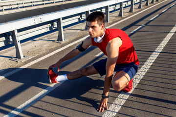 Fototapeta na wymiar Young athlete man stretching his muscles before running on bridge on sunny day.