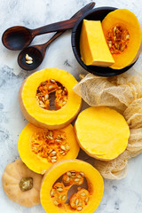 Ripe pumpkin sliced and wooden spoons.