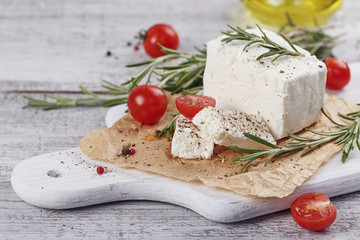 Fresh feta cheese with rosemary on white wooden serving board