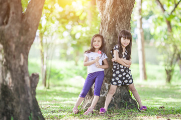 Fototapeta premium Two little girls relaxing play in the park and eat lollipops