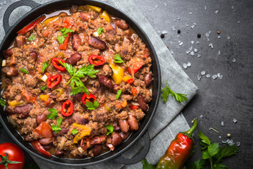 Chili con carne in iron pan on black background. Traditional mexican food.