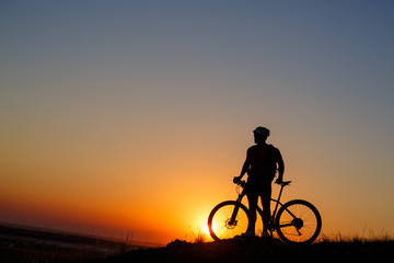 Fototapeta na wymiar Silhouette man stand with mountain bike on the meadow