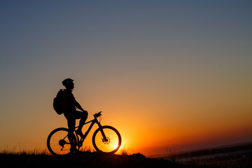 Obraz na płótnie Canvas Silhouette man stand with mountain bike on the meadow