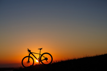 Fototapeta na wymiar Silhouette of a bike on the hills at sunset.