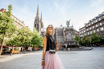 Lifestyle portrait of a woman traveling in front of the famous cathedral in Clermont-Ferrand city...