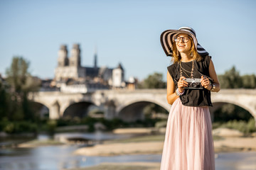 Young woman tourist standing on the beautiful cityscape background during the sunset in Orleans city, France