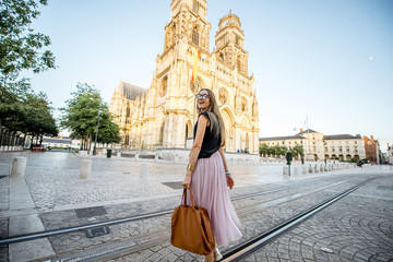 Lifestyle portrait of a woman walking near the famous cathedral during the sunset in Orleans, France - obrazy, fototapety, plakaty