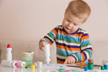 Portrait of cute toddler boy drawing at home with colorful paints and brush. Creative child having fun. Educational and learning concept