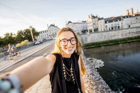 Young woman tourist making selfie photo on the beautiful cityscape background in Orleans, France