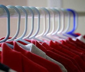 Fototapeta premium Red and one gray school uniform shirts on hangers. Selective focus.