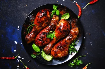 Zelfklevend Fotobehang Baked chicken legs in spicy glaze sauce on black plate, low key, top view © 5ph